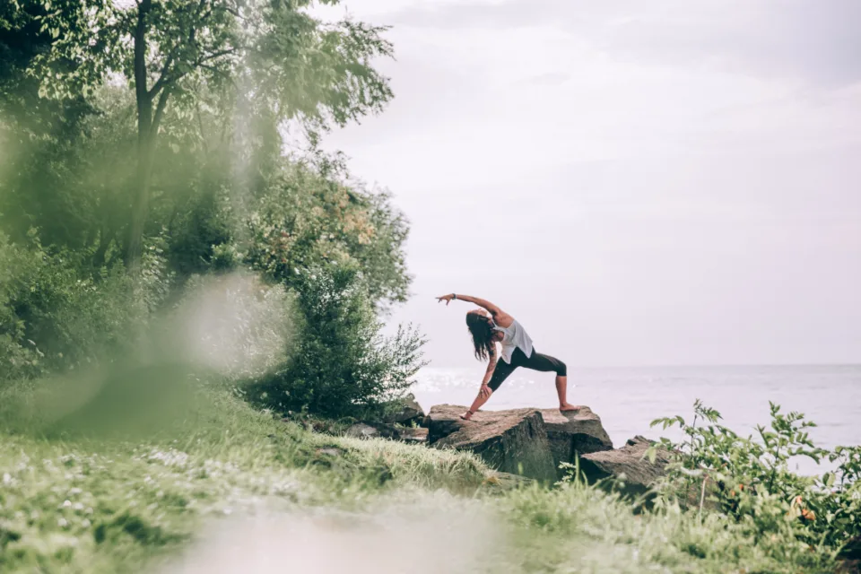 Mujer practicando yoga sobre una roca frente al mar